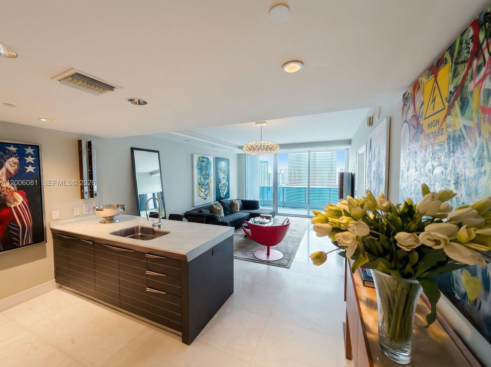 A modern kitchen island with a sink sits in front of an open-concept living area — 200 BISCAYNE BLVD WAY # 4310, Miami FL 33131, MIAMI, FL