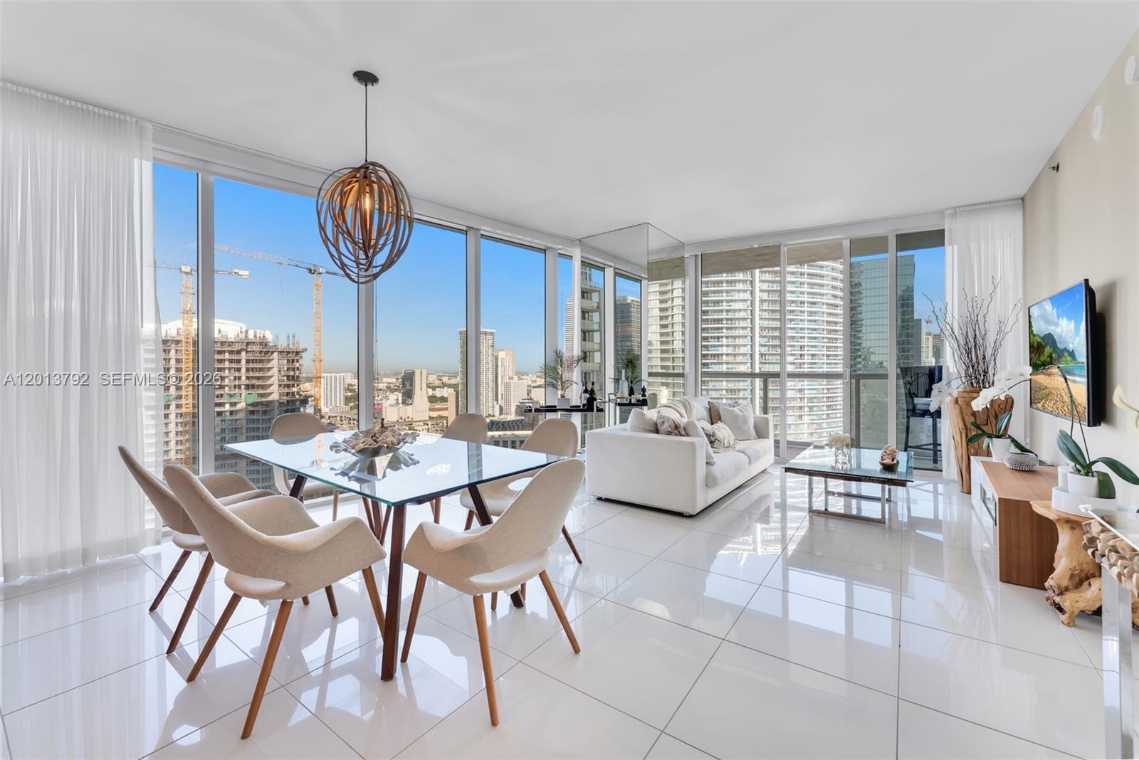 A bright, modern living and dining area features floor-to-ceiling windows, white tile floors, and city views — 475 Brickell Ave # 3515, Miami FL 33131, MIAMI, FL