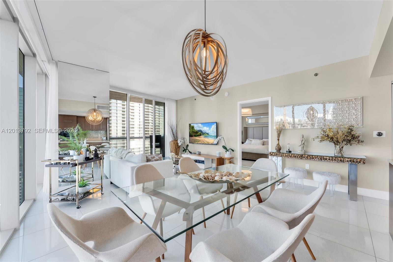 A dining area with a glass table and modern chairs sits before a living room — 475 Brickell Ave # 3515, Miami FL 33131, MIAMI, FL