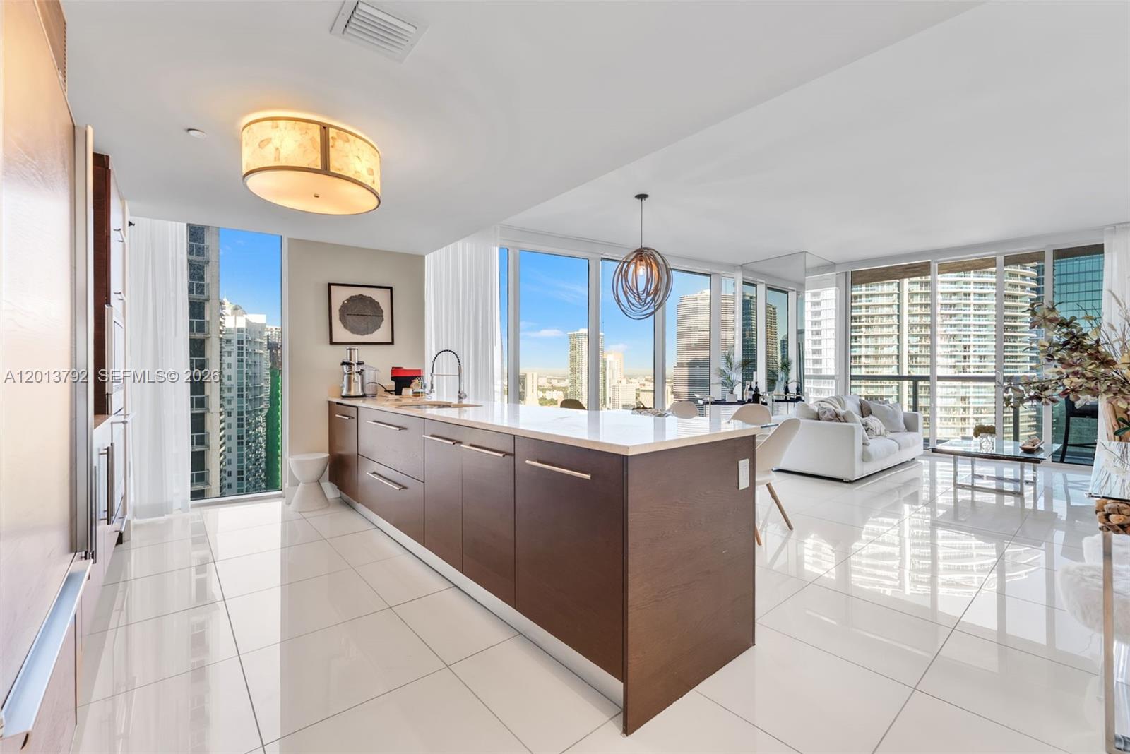 A modern kitchen with dark wood cabinetry and a white island overlooks a city skyline — 475 Brickell Ave # 3515, Miami FL 33131, MIAMI, FL