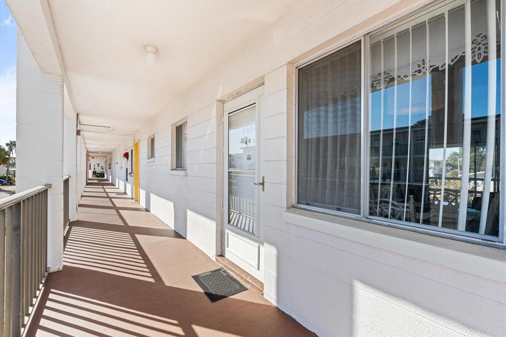 An exterior walkway with white block walls, a screen door, and a large window — 5902 GARDEN LANE UNIT A24, BRADENTON, FL