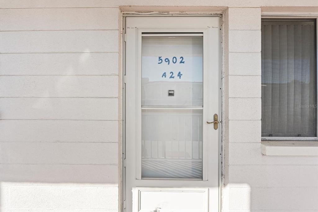 A white exterior door with a glass storm door and the numbers 5902 A24 displayed — 5902 GARDEN LANE UNIT A24, BRADENTON, FL