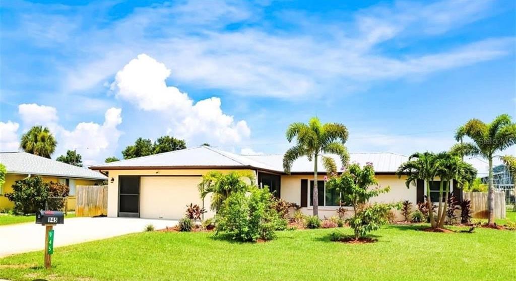 A single-story house with a metal roof, a two-car garage, and palm trees in front — 945 CHEVY CHASE STREET, PORT CHARLOTTE, FL