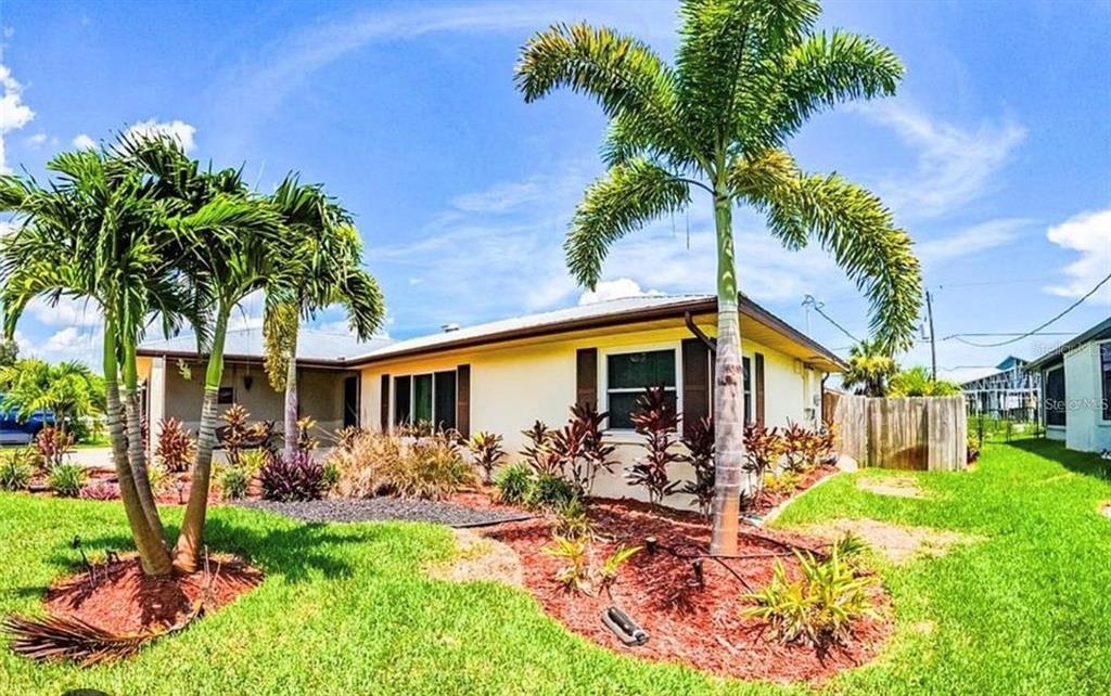 A single-story house with a palm tree in the front yard under a blue sky — 945 CHEVY CHASE STREET, PORT CHARLOTTE, FL