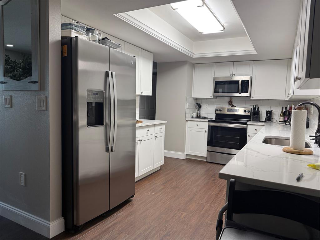 A kitchen features white cabinets, stainless steel appliances, and a quartz countertop island — 945 CHEVY CHASE STREET, PORT CHARLOTTE, FL