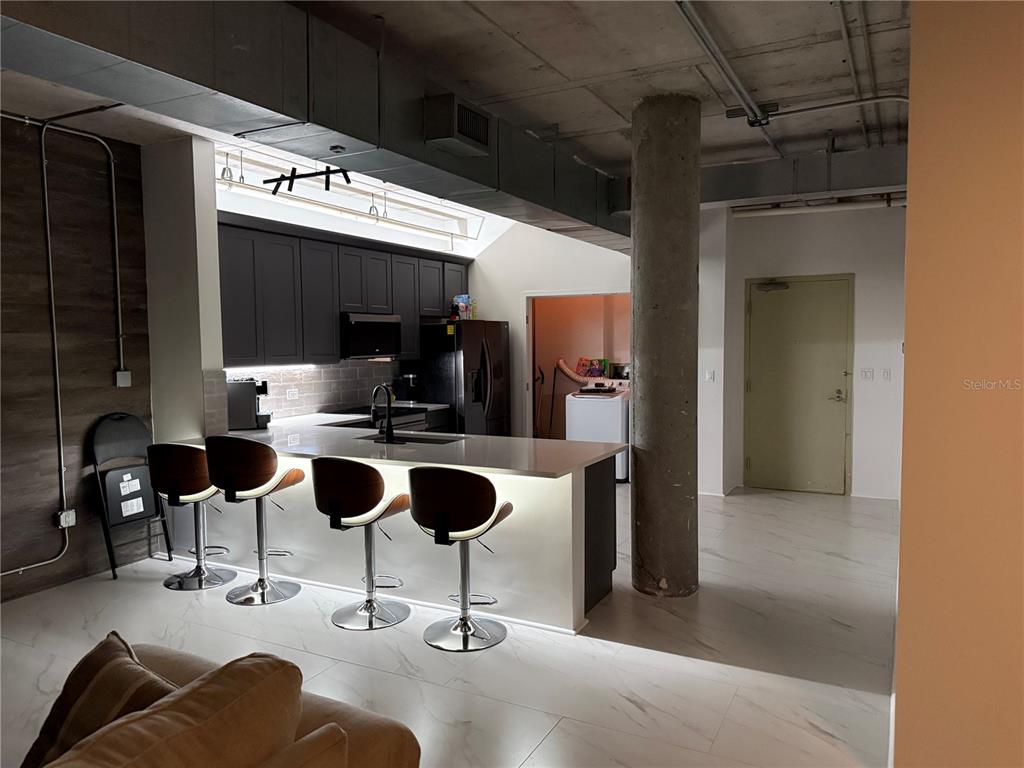 A kitchen with dark cabinets, a breakfast bar, and a concrete pillar in an open-concept space — 10 N SUMMERLIN AVENUE UNIT 34, ORLANDO, FL
