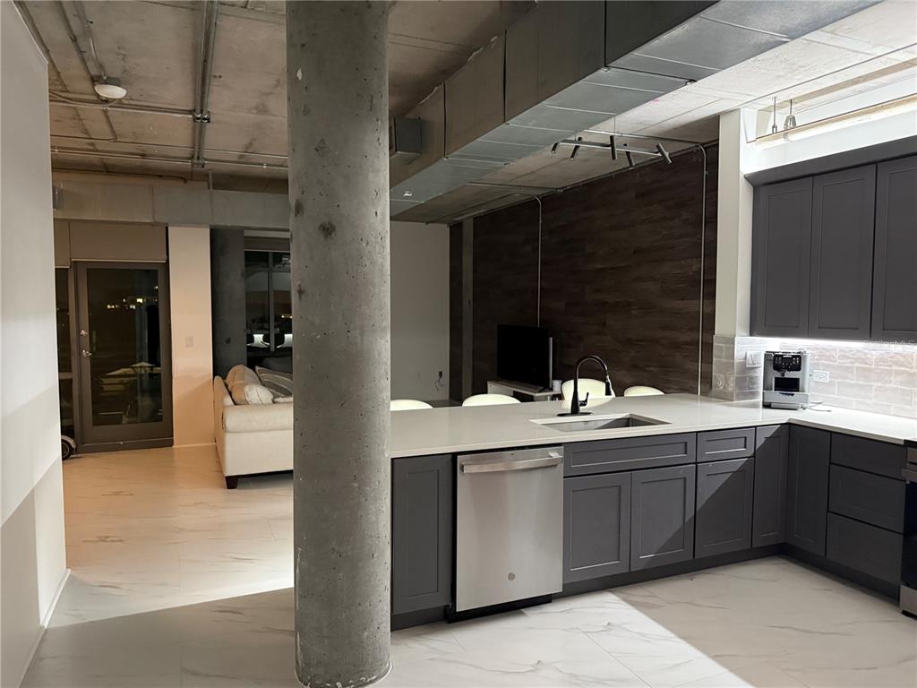 A modern kitchen with dark gray cabinets and a concrete pillar opens into a living area — 10 N SUMMERLIN AVENUE UNIT 34, ORLANDO, FL