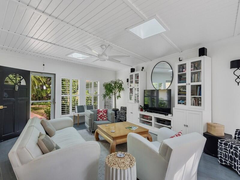 A bright living room features white paneled ceilings, skylights, a television, and white furniture — VERO BEACH, FL