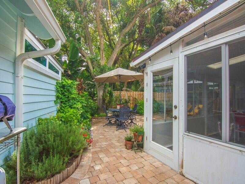 A paved patio area sits between a light blue house and a screened-in porch — VERO BEACH, FL