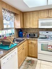 A kitchen features light wood cabinets, a white stove, a dishwasher, and a window — 1656 S LAKE AVENUE UNIT 3, CLEARWATER, FL