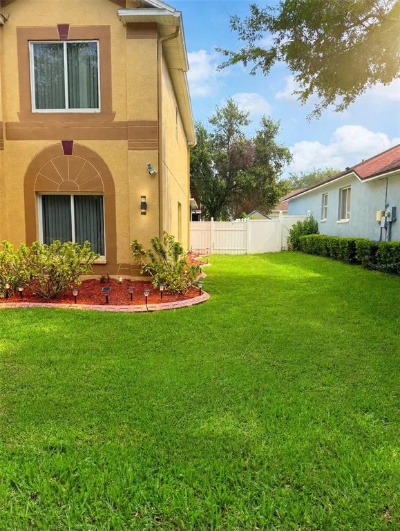 A side view of a two-story tan stucco house with a green lawn and landscaping — 4236 BALINGTON DRIVE, VALRICO, FL