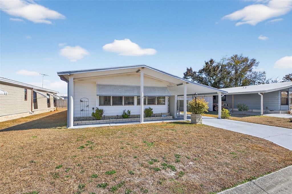 A single-story manufactured home with a carport and a dry, grassy front yard — 3836 WILLIAM HUME DRIVE, ZEPHYRHILLS, FL