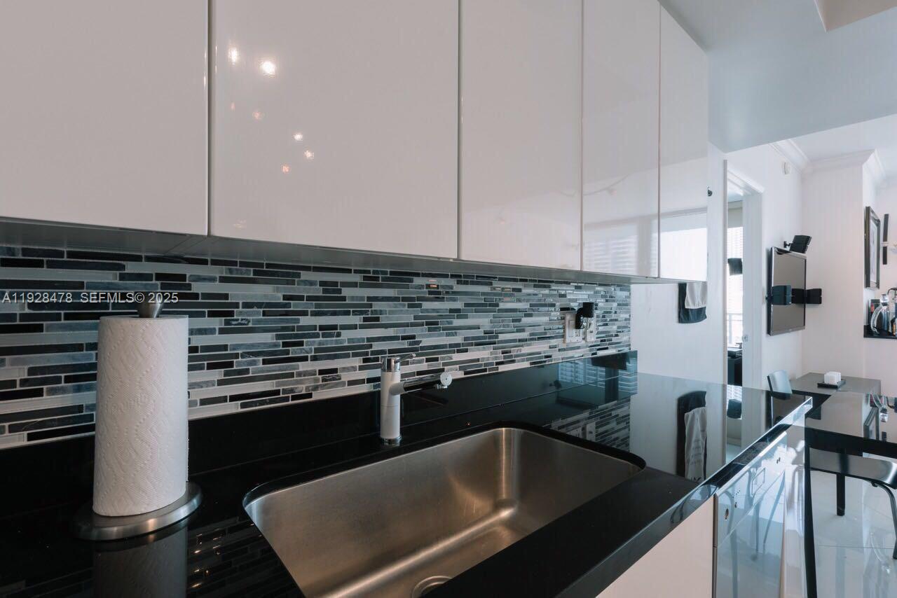 A kitchen features white cabinets, a black countertop, and a multi-colored glass tile backsplash — 92 SW 3RD St # 1512, Miami FL 33130, MIAMI, FL