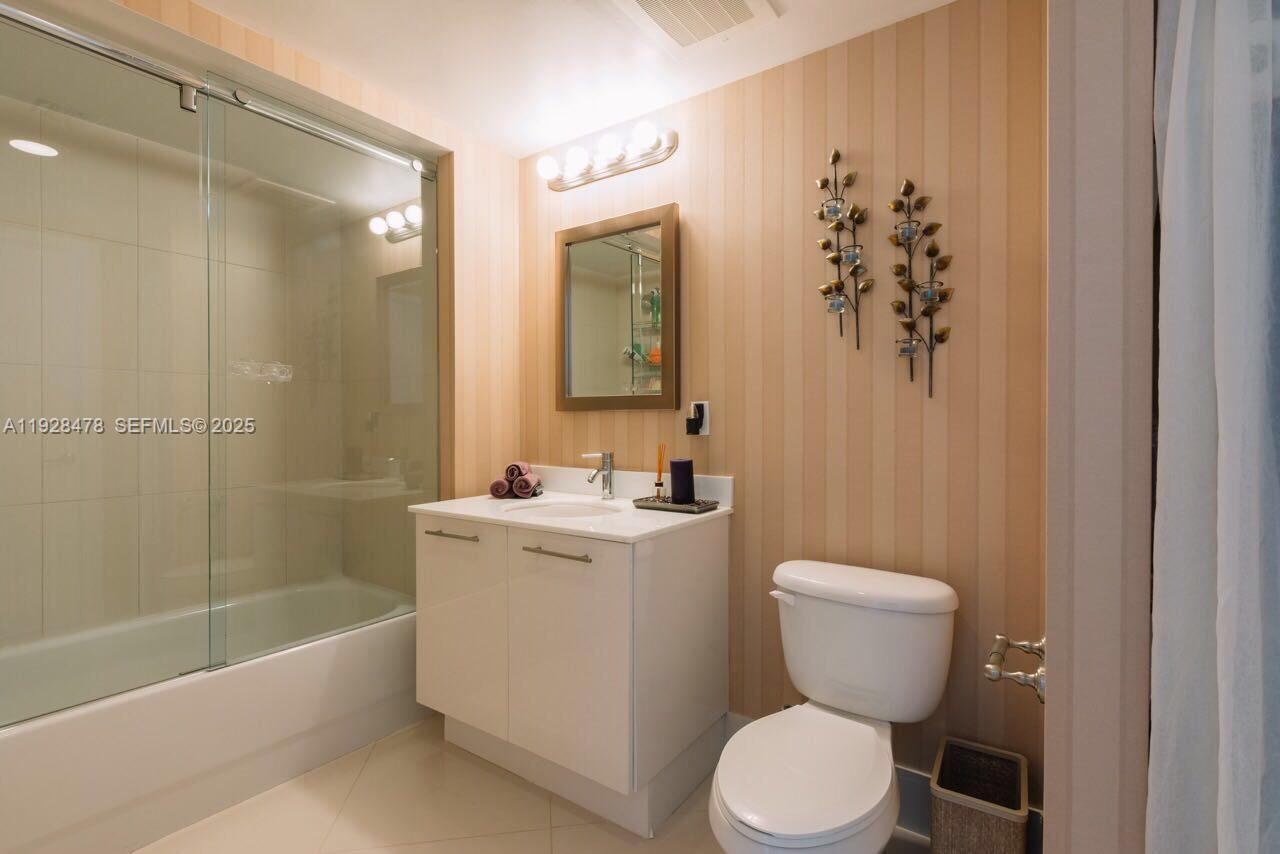 A bathroom features a white vanity, a glass-enclosed shower, and a toilet against striped wallpaper — 92 SW 3RD St # 1512, Miami FL 33130, MIAMI, FL
