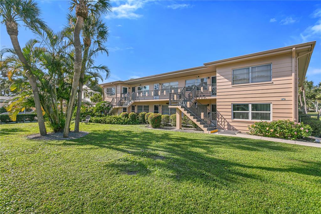 A two-story apartment building with tan siding, exterior staircases, and a grassy lawn — 216 36TH AVENUE N UNIT 202B, ST PETERSBURG, FL