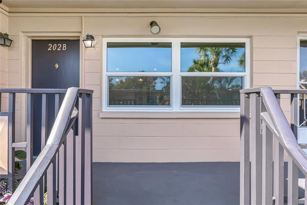 A dark front door labeled 202B sits next to a large window on a balcony — 216 36TH AVENUE N UNIT 202B, ST PETERSBURG, FL