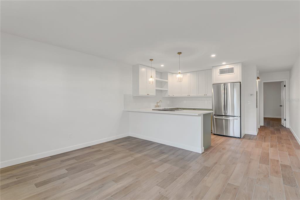 A kitchen with white cabinets and a breakfast bar opens to a living area — 216 36TH AVENUE N UNIT 202B, ST PETERSBURG, FL