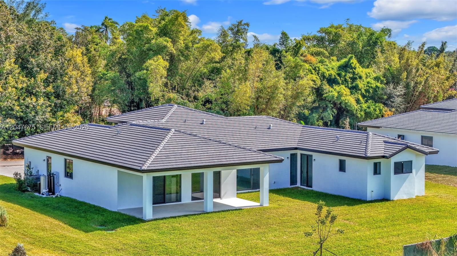 The rear exterior of a white single-story house with a dark tiled roof and patio — 23120 SW 154 CT, Miami FL 33170, MIAMI, FL