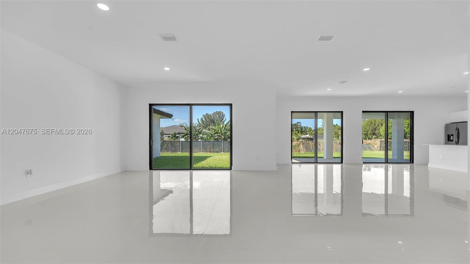 A bright, open-concept living area features white walls, glossy tile floors, and multiple sliding doors — 23120 SW 154 CT, Miami FL 33170, MIAMI, FL