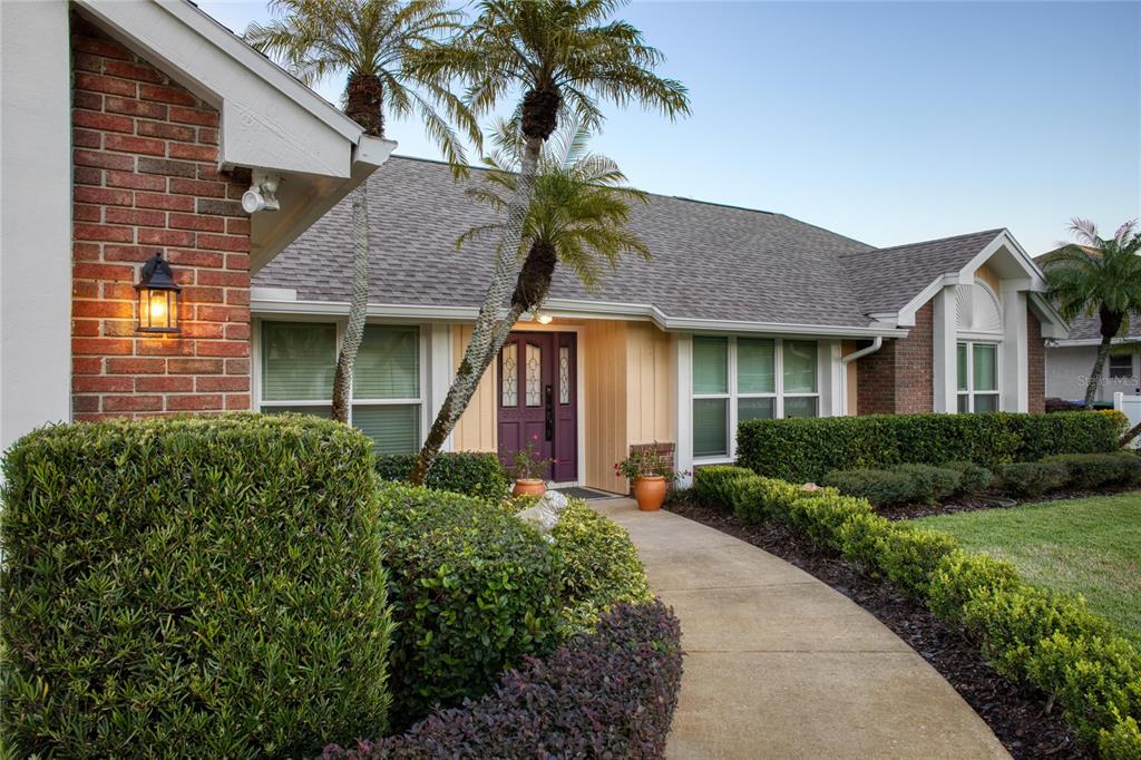 A brick and siding house features a purple front door and a concrete walkway — 9052 PALOS VERDE DRIVE, ORLANDO, FL