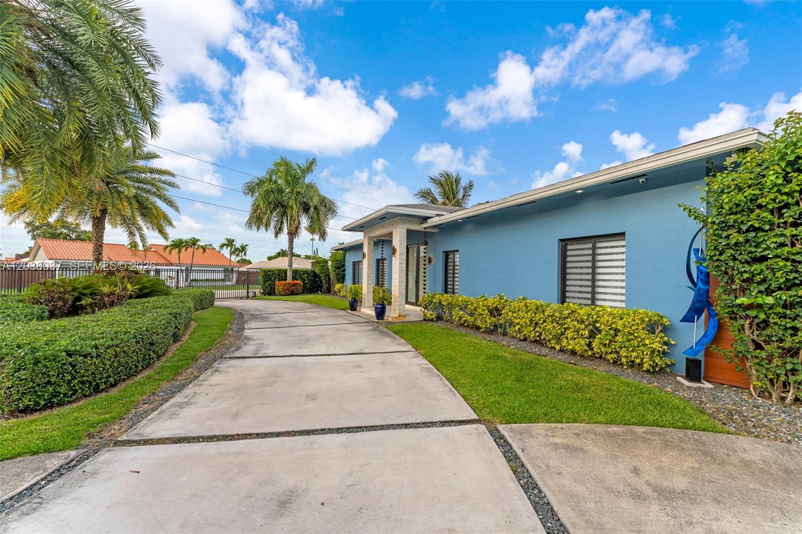 A blue house with a concrete driveway and landscaped yard under a cloudy sky — 1201 SW 92nd Ave, Miami FL 33174, MIAMI, FL