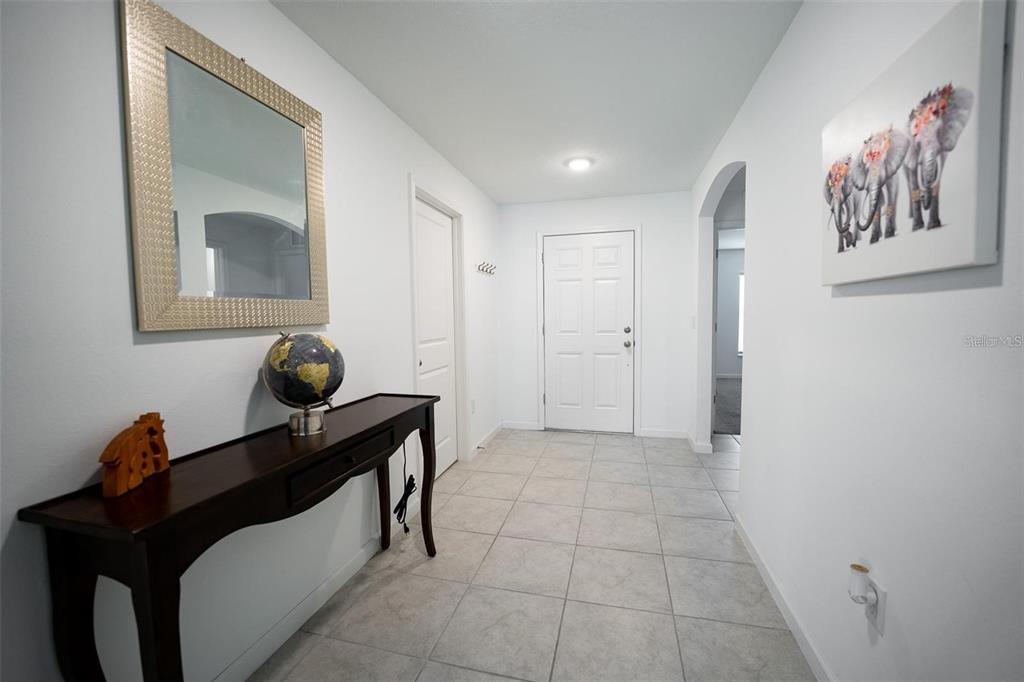 A tiled entryway features a console table with a globe, a mirror, and elephant wall art — 3473 YARIAN DRIVE, HAINES CITY, FL