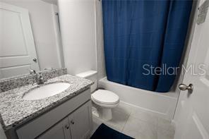 A bathroom features a granite vanity, a white toilet, and a blue shower curtain — 3473 YARIAN DRIVE, HAINES CITY, FL