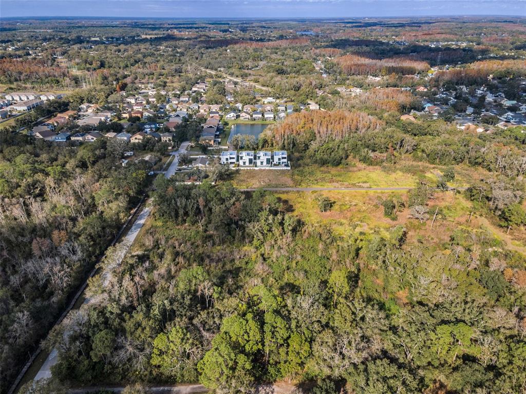 An aerial view shows a wooded lot adjacent to a residential neighborhood and a pond — 410 SKYTRAIL, TAMPA, FL