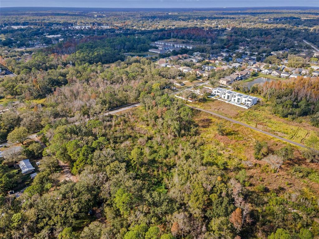 An aerial view shows a large, wooded lot adjacent to a residential neighborhood and road — 410 SKYTRAIL, TAMPA, FL