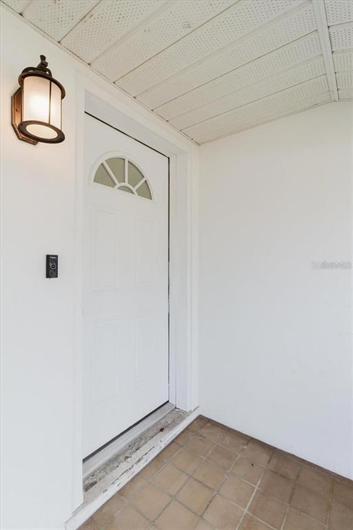A white front door with a small arched window sits on a tiled porch — 103 N METEOR AVENUE, CLEARWATER, FL