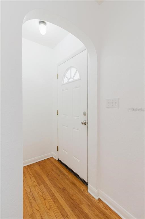 An arched entryway leads to a white door with a small window and hardwood floors — 103 N METEOR AVENUE, CLEARWATER, FL