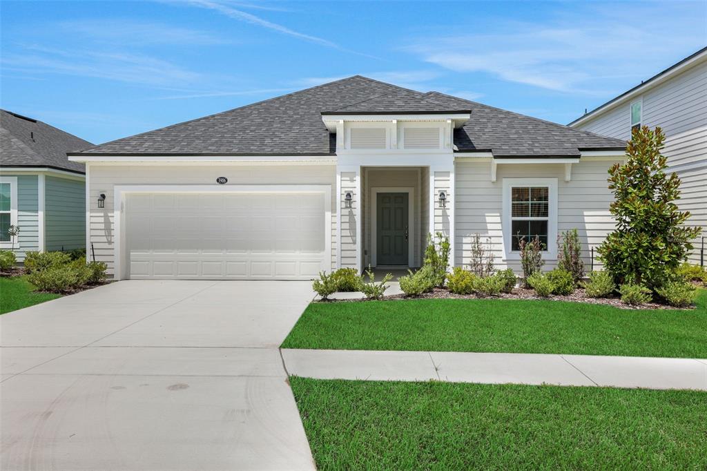 A single-story house with light siding, a two-car garage, and a front entryway — 3906 HOLSTEIN WAY, GREEN COVE SPRINGS, FL