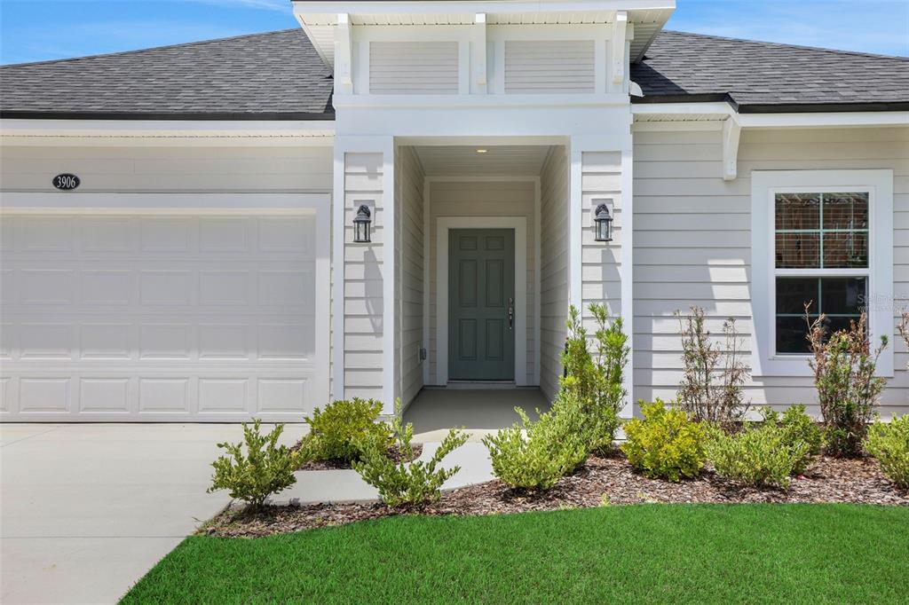 The exterior of a single-story house features light gray siding, a white garage, and a green door — 3906 HOLSTEIN WAY, GREEN COVE SPRINGS, FL