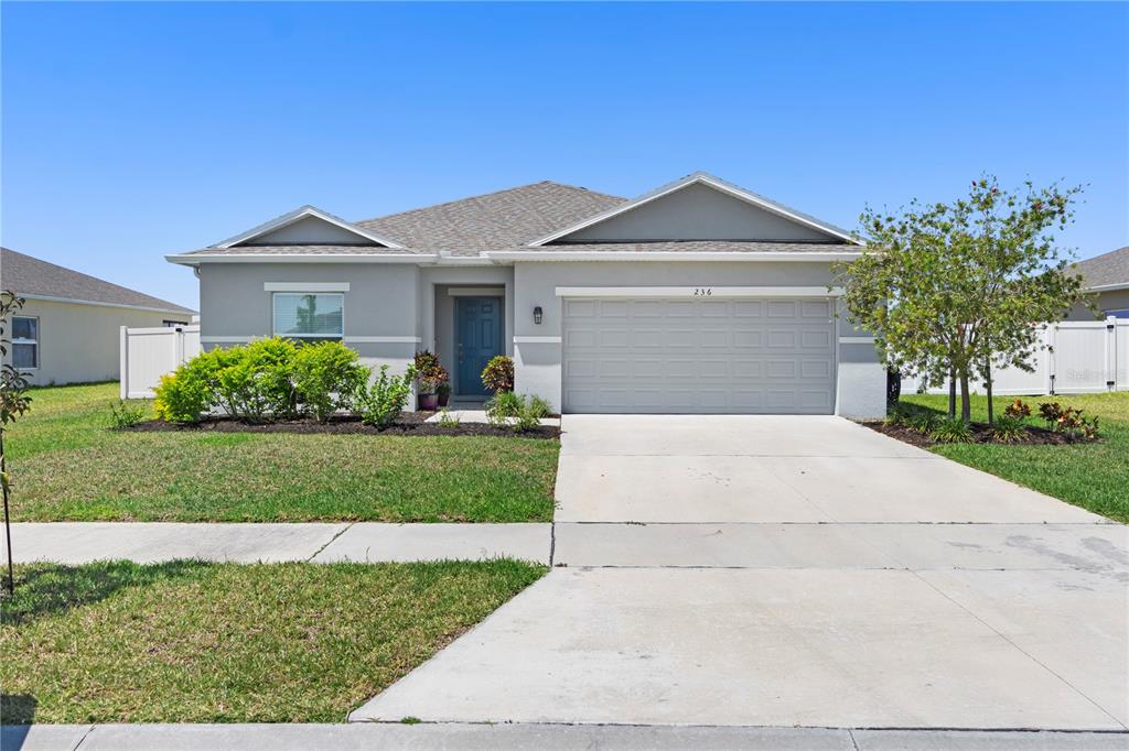 A single-story house with a gray exterior, a blue front door, and a two-car garage — 236 AQUAMARINE LANE, KISSIMMEE, FL