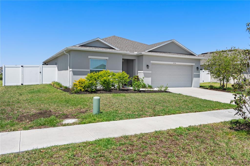 A single-story house with a gray exterior, a two-car garage, and a white vinyl fence — 236 AQUAMARINE LANE, KISSIMMEE, FL