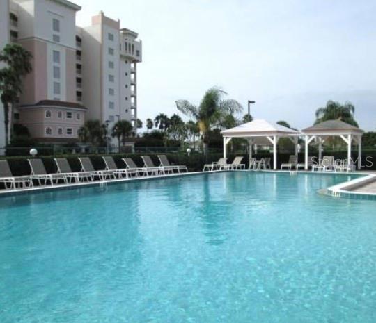 A swimming pool with lounge chairs and two gazebos sits beside a tall apartment building — 2925 TERRA CEIA BAY BOULEVARD UNIT 2203, PALMETTO, FL