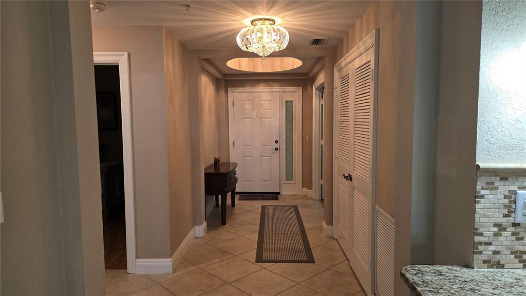 A tiled entryway features a crystal chandelier, a white front door, and louvered closet doors — 2925 TERRA CEIA BAY BOULEVARD UNIT 2203, PALMETTO, FL