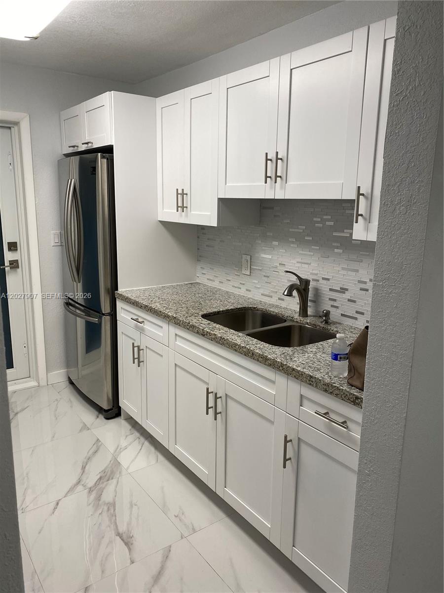 A kitchen features white shaker cabinets, granite countertops, a stainless steel refrigerator, and tiled floors — 1030 9th St # 204, Miami Beach FL 33139, MIAMI BEACH, FL