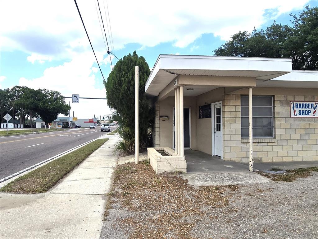 A single-story commercial building with a barber shop sign sits beside a sidewalk and road — 620 S COLLINS STREET, PLANT CITY, FL