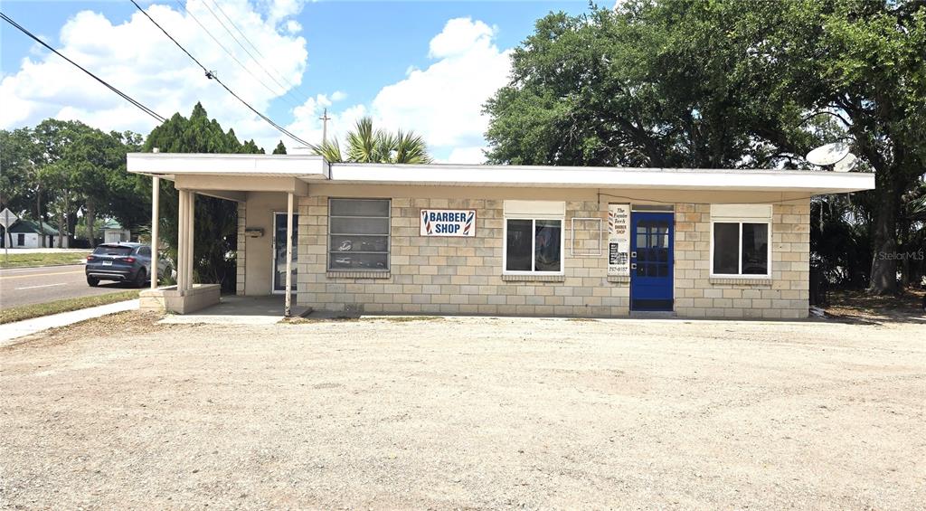 A single-story commercial building with a gravel parking lot and a blue front door — 620 S COLLINS STREET, PLANT CITY, FL