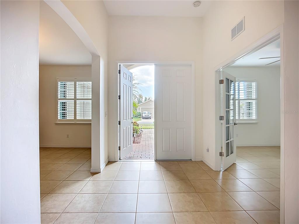 An entryway with tiled floors leads to an open front door showing a driveway — 5384 LAYTON DRIVE, VENICE, FL