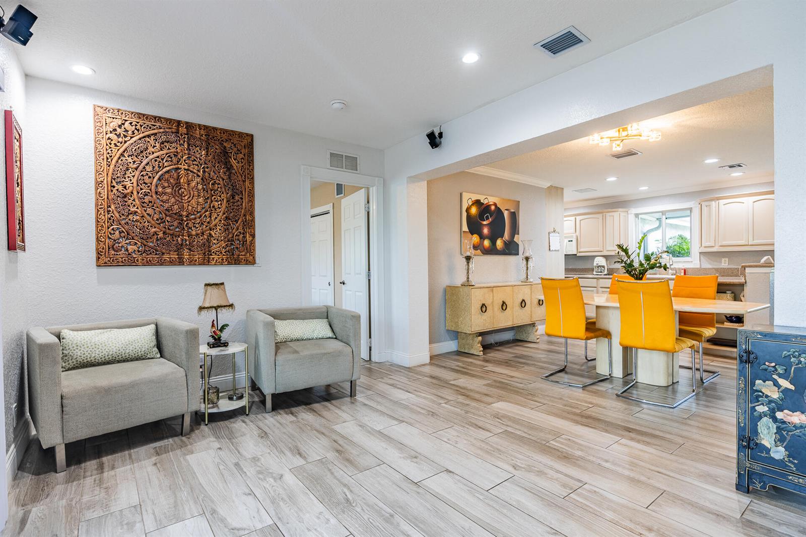 A living area with two gray armchairs leads into a dining room with yellow chairs — 801 SE 5th Terrace, Pompano Beach FL 33060, POMPANO BEACH, FL