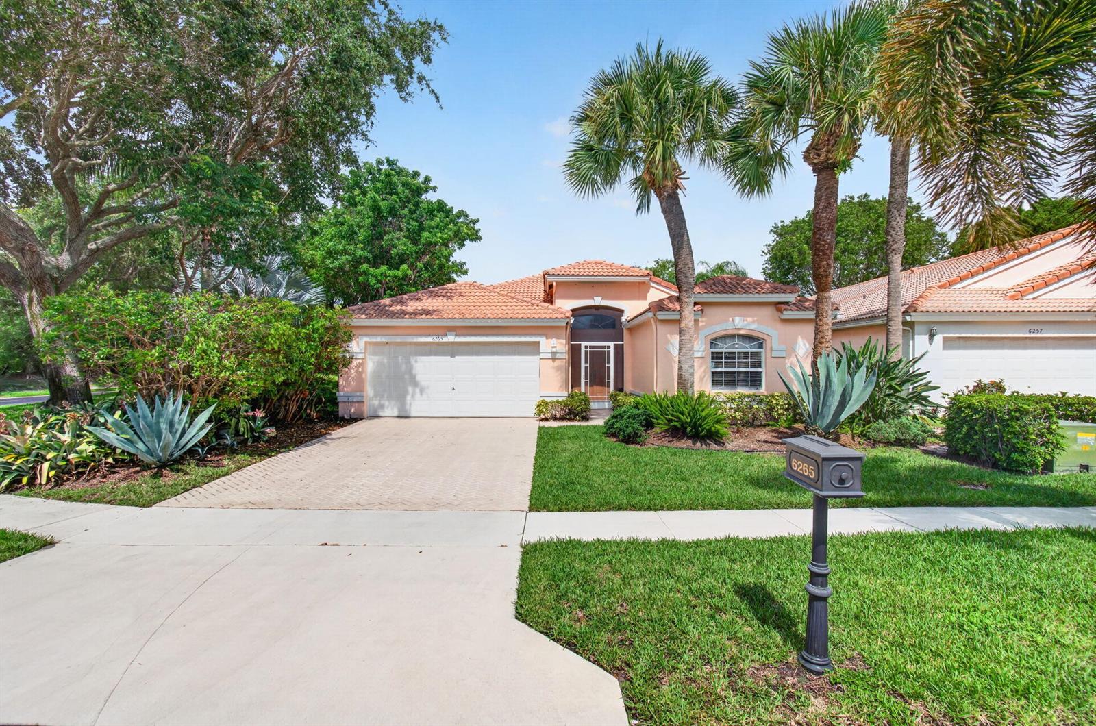 A single-story peach-colored house with a tile roof, two-car garage, and palm trees — 6265 Coral Reef Terrace, Boynton Beach FL 33437, BOYNTON BEACH, FL