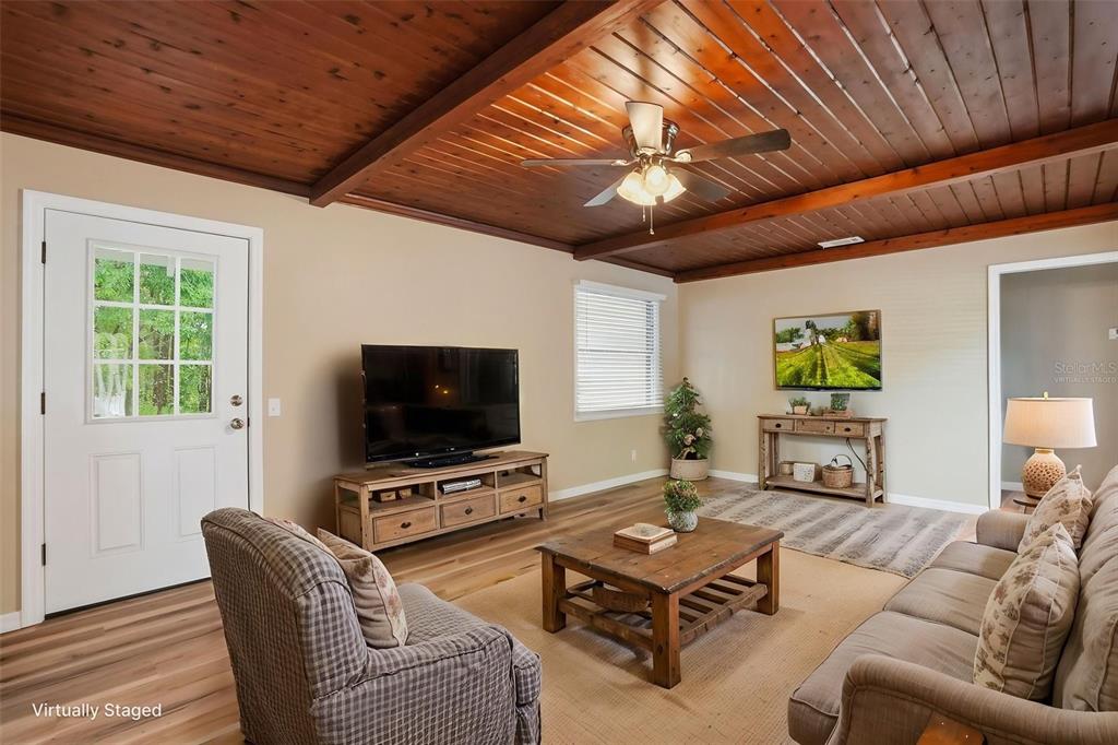 A living room features a wood-plank ceiling, ceiling fan, and light-colored walls — 65 MARKHAM LANE, BROOKSVILLE, FL