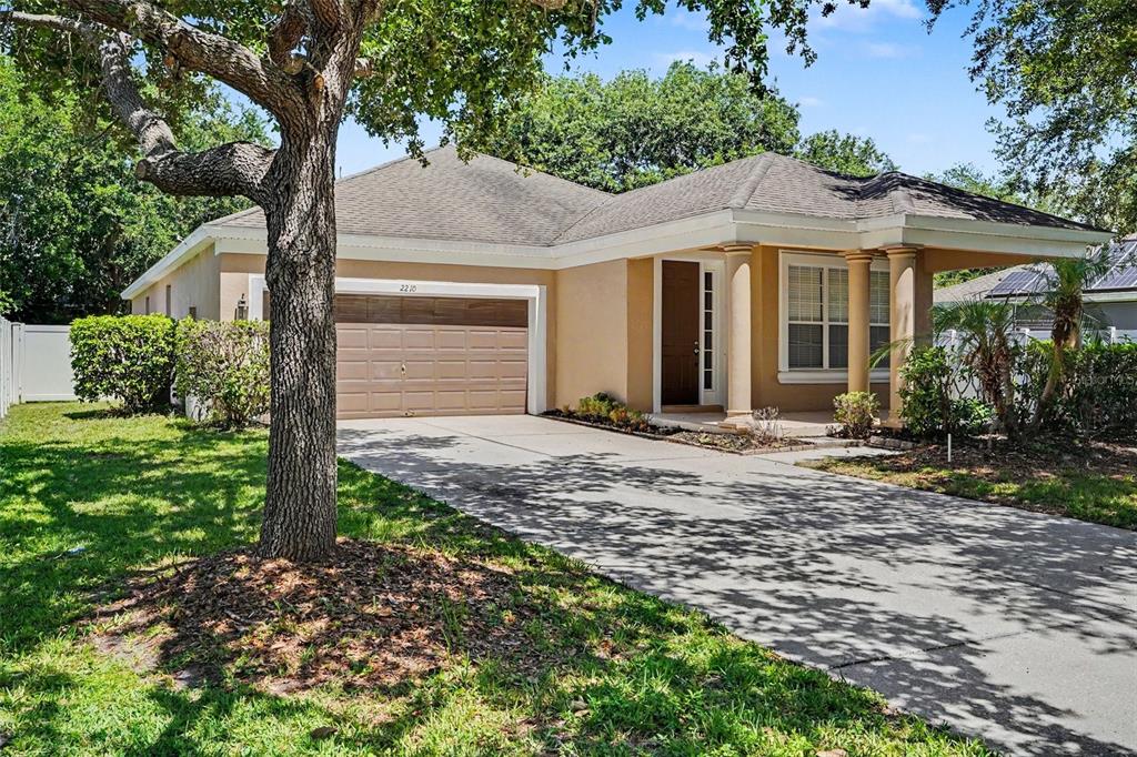 A single-story house with a tan exterior, a two-car garage, and a covered front porch — 2210 GRANGER AVENUE, KISSIMMEE, FL