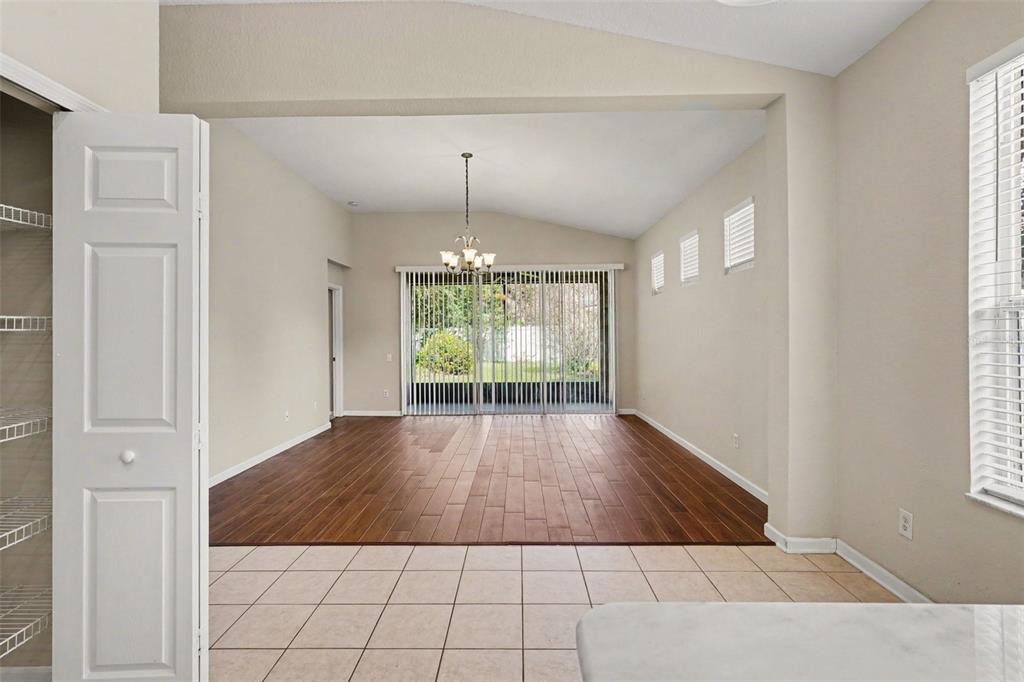 A room with tile flooring in the foreground and wood-look flooring in the living area — 2210 GRANGER AVENUE, KISSIMMEE, FL
