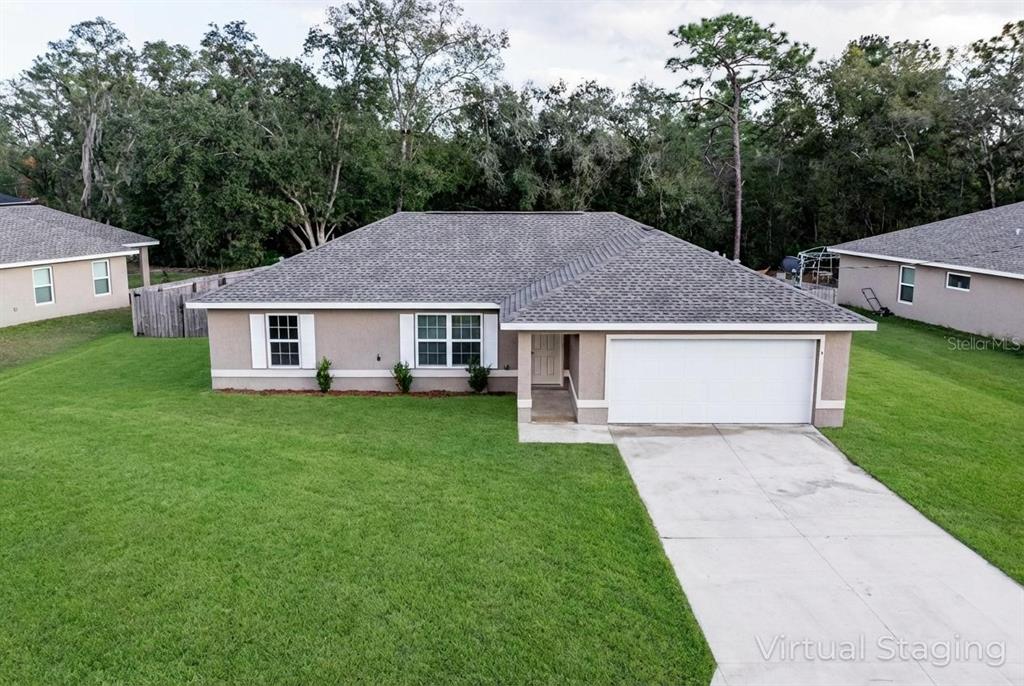An exterior view of a single-story house with a gray roof and a concrete driveway — 5 MALAUKA RADIAL CIRCLE, OCKLAWAHA, FL