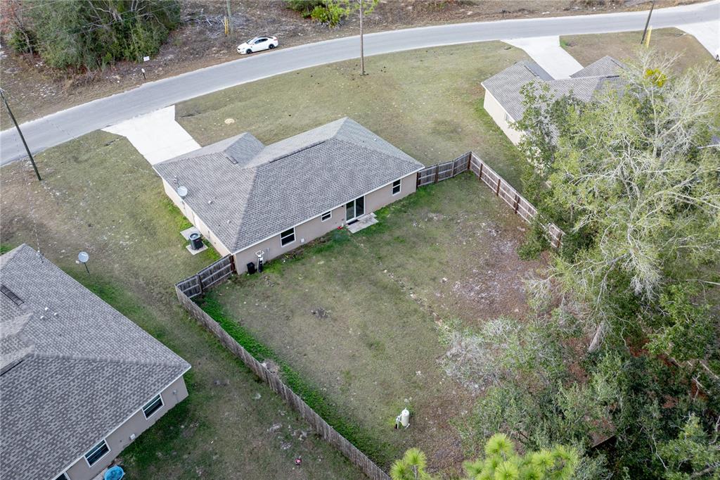 An aerial view shows a single-story house with a fenced backyard and a paved driveway — 5 MALAUKA RADIAL CIRCLE, OCKLAWAHA, FL