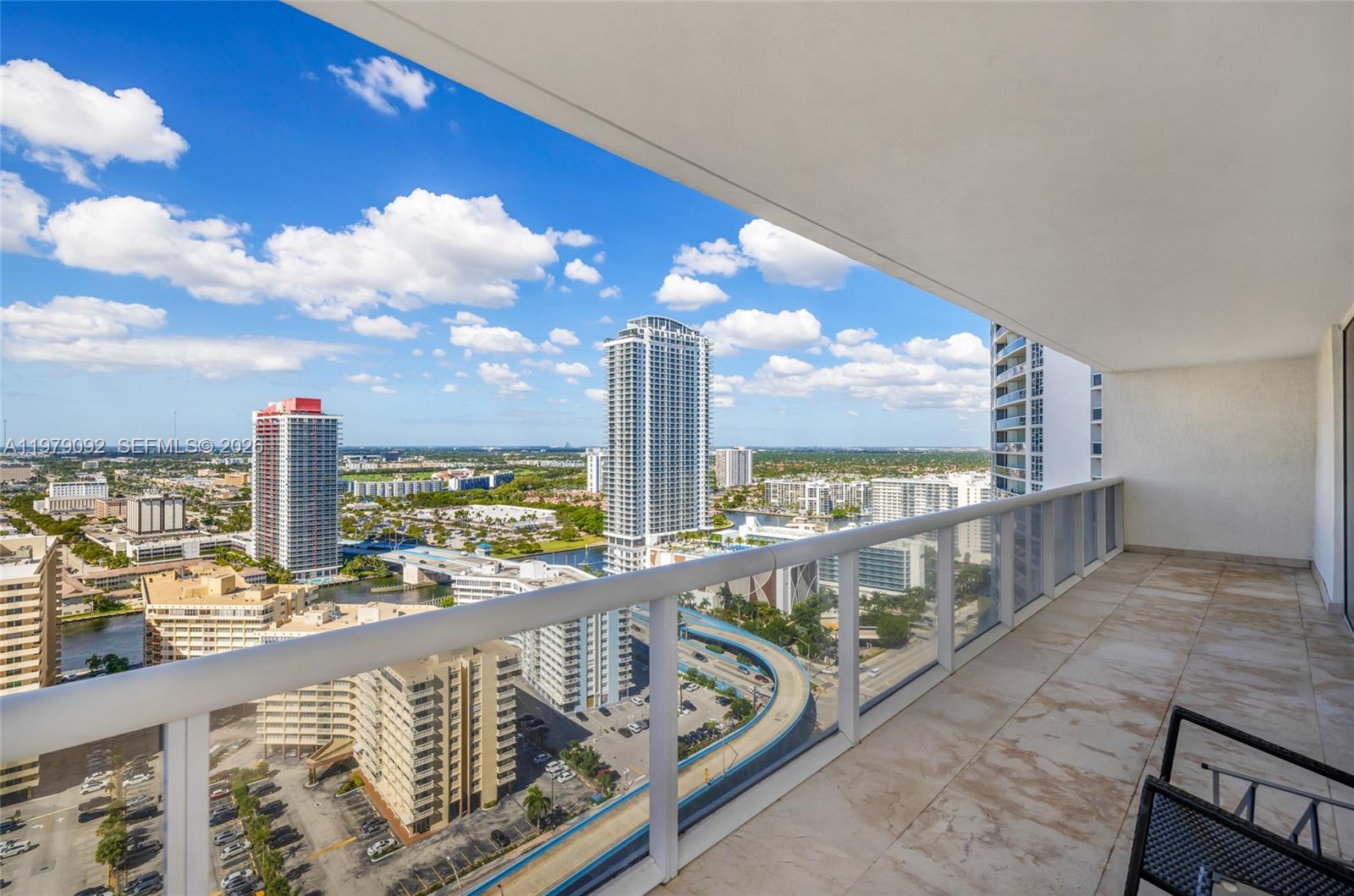 A high-rise balcony with tiled flooring overlooks a city skyline and a curved highway — 1830 S Ocean Dr # 2806, Hallandale Beach FL 33009, HALLANDALE BEACH, FL