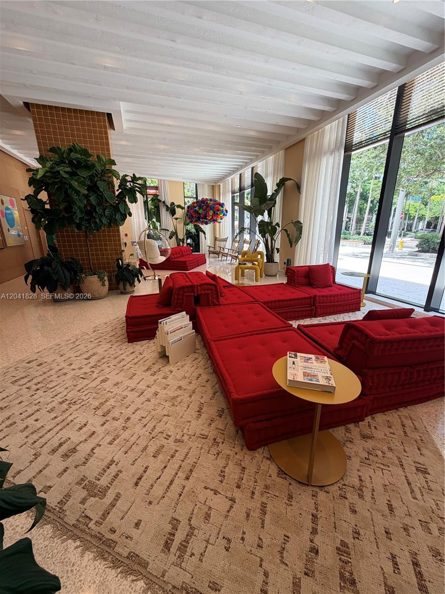 A modern lobby features red modular seating, large potted plants, and floor-to-ceiling windows — 90 NE 32nd St # 707, Miami FL 33137, MIAMI, FL